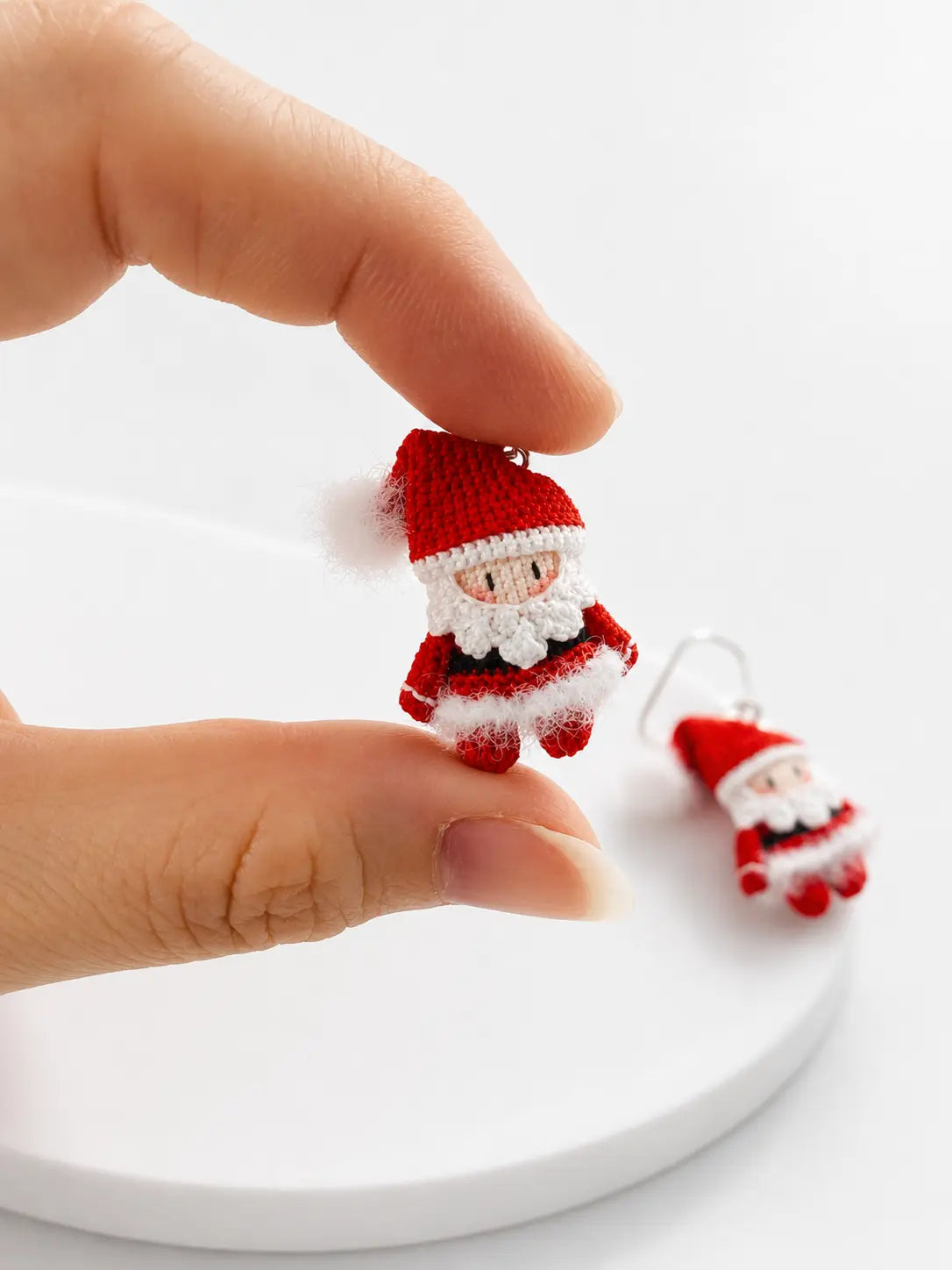 Close-up of a hand holding a miniature handmade Santa Claus crochet earring