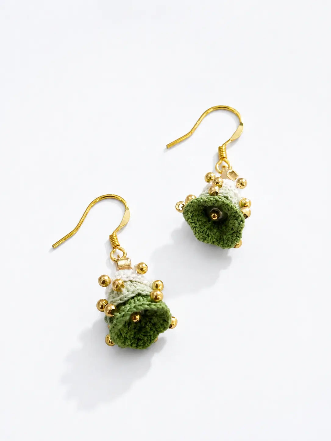 Detailed view of handmade Christmas tree drop earrings with layered green crochet, pearl accents and gold hooks