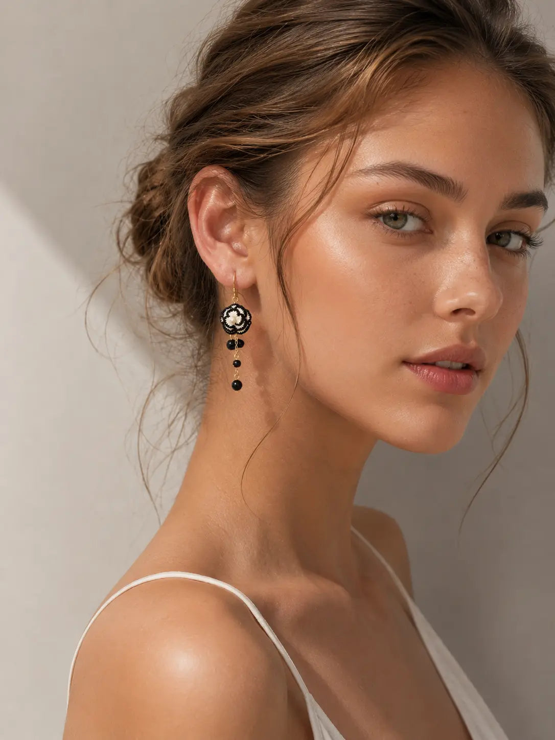 Woman wearing black and white camellia drop earrings with an elegant updo