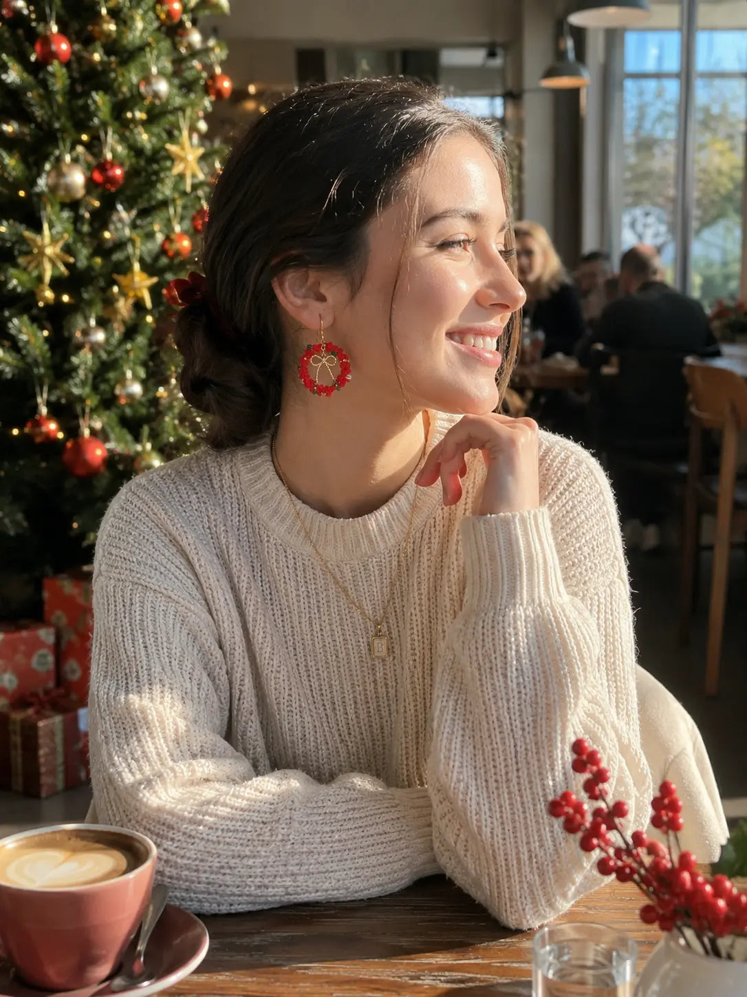 Woman wearing red Christmas wreath crochet earrings in a cosy cafe with festive holiday decor