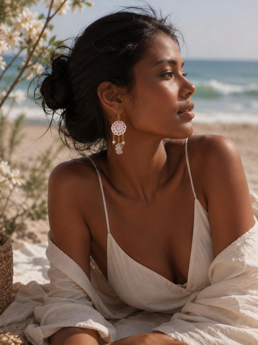 Woman wearing purple dreamcatcher, crystal and pearl drop earrings while seated by the beach in soft natural light.
