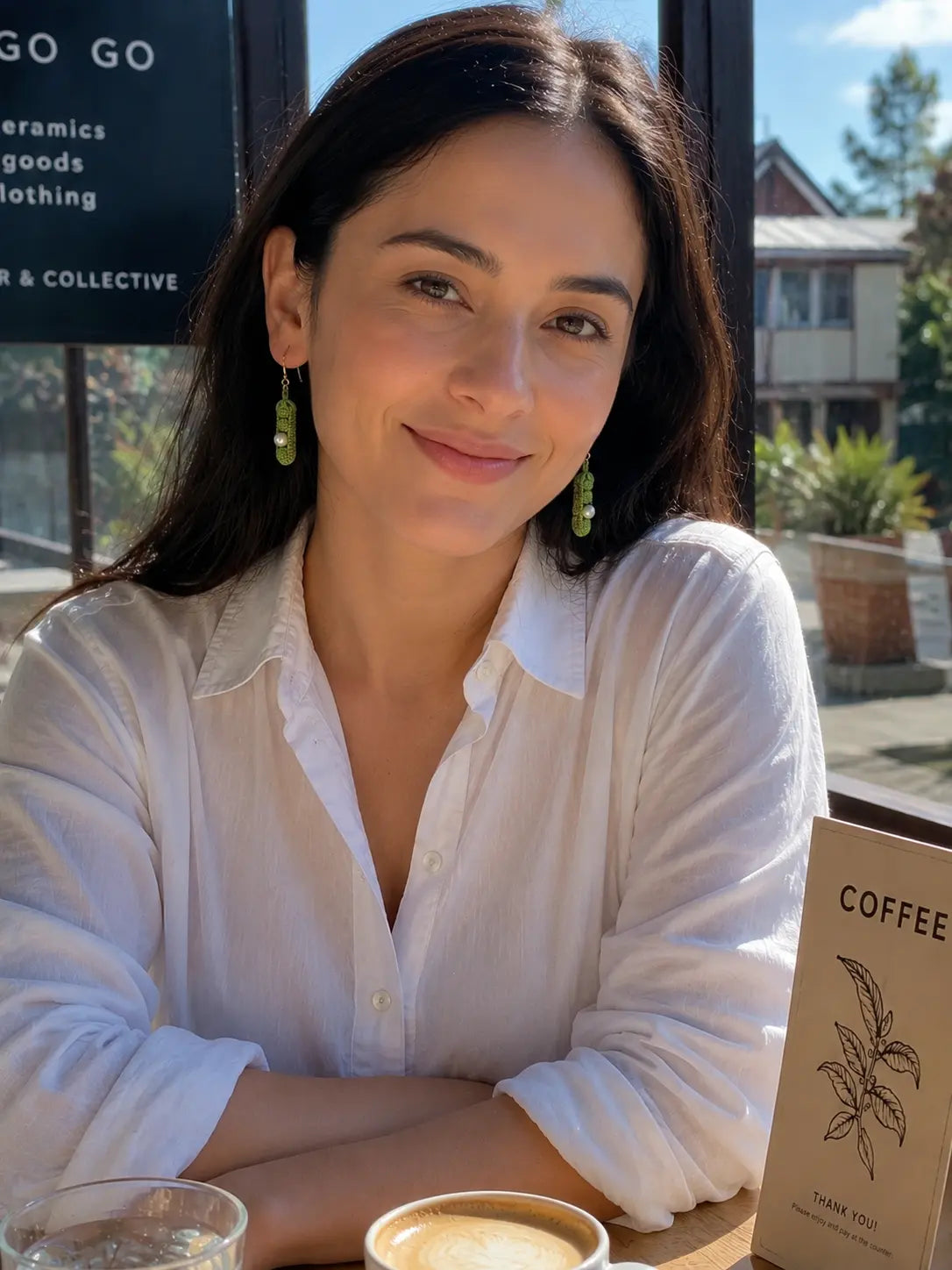 Lifestyle photo of a model wearing micro crochet Pea Pod Earrings at a café, styled with a relaxed white outfit.