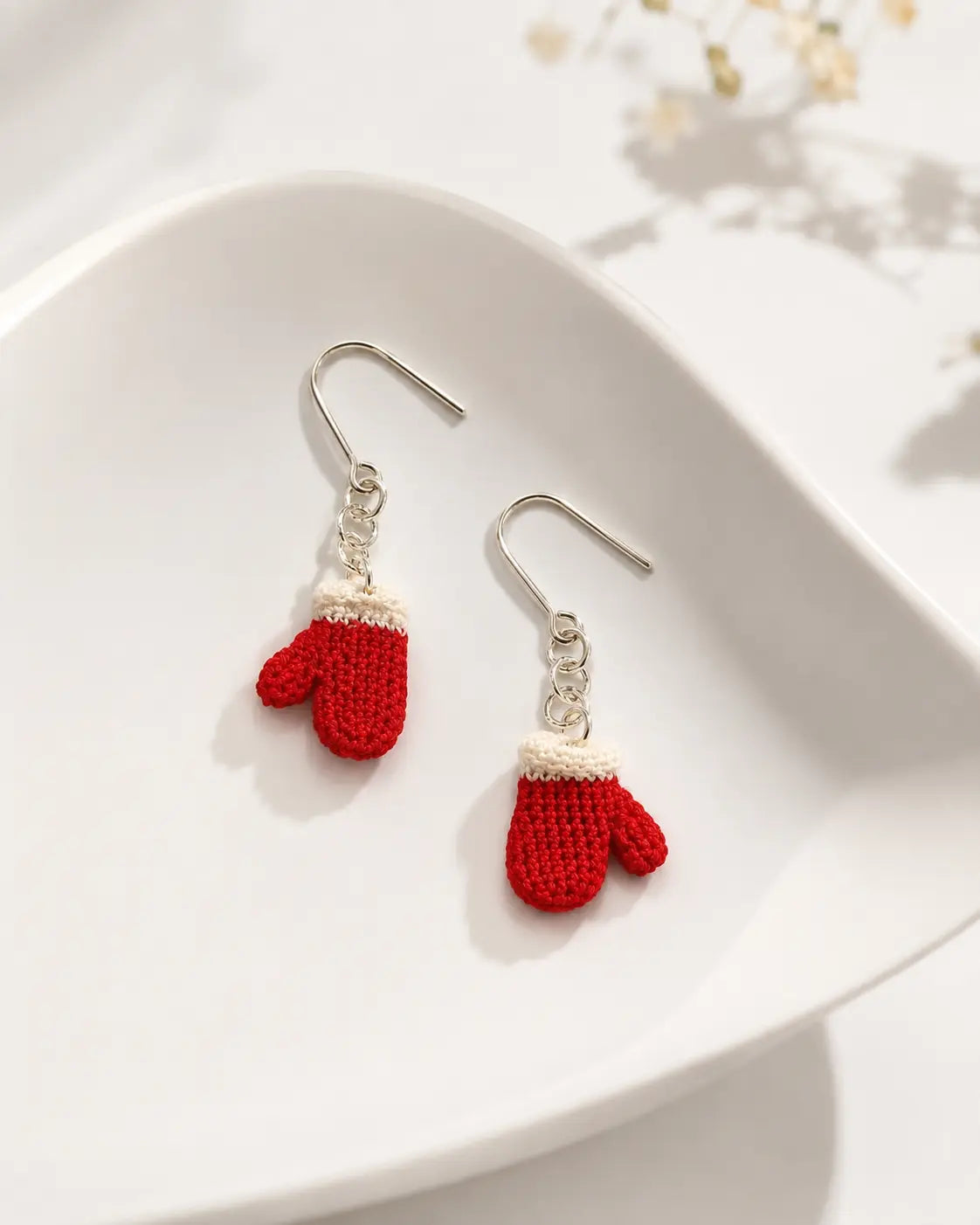 Detailed view of handmade red Santa mitten drop earrings with white crochet cuffs and delicate silver-tone hooks