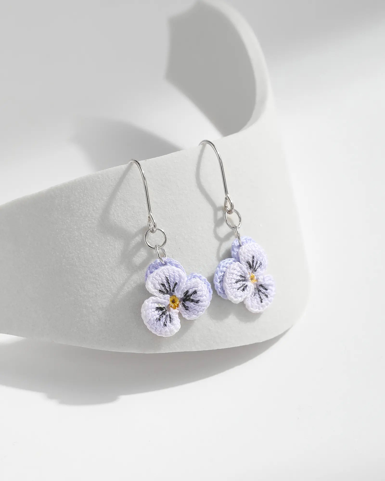 Light purple micro crochet Pansy Drop Earrings with silver hooks displayed on a white jewellery stand.
