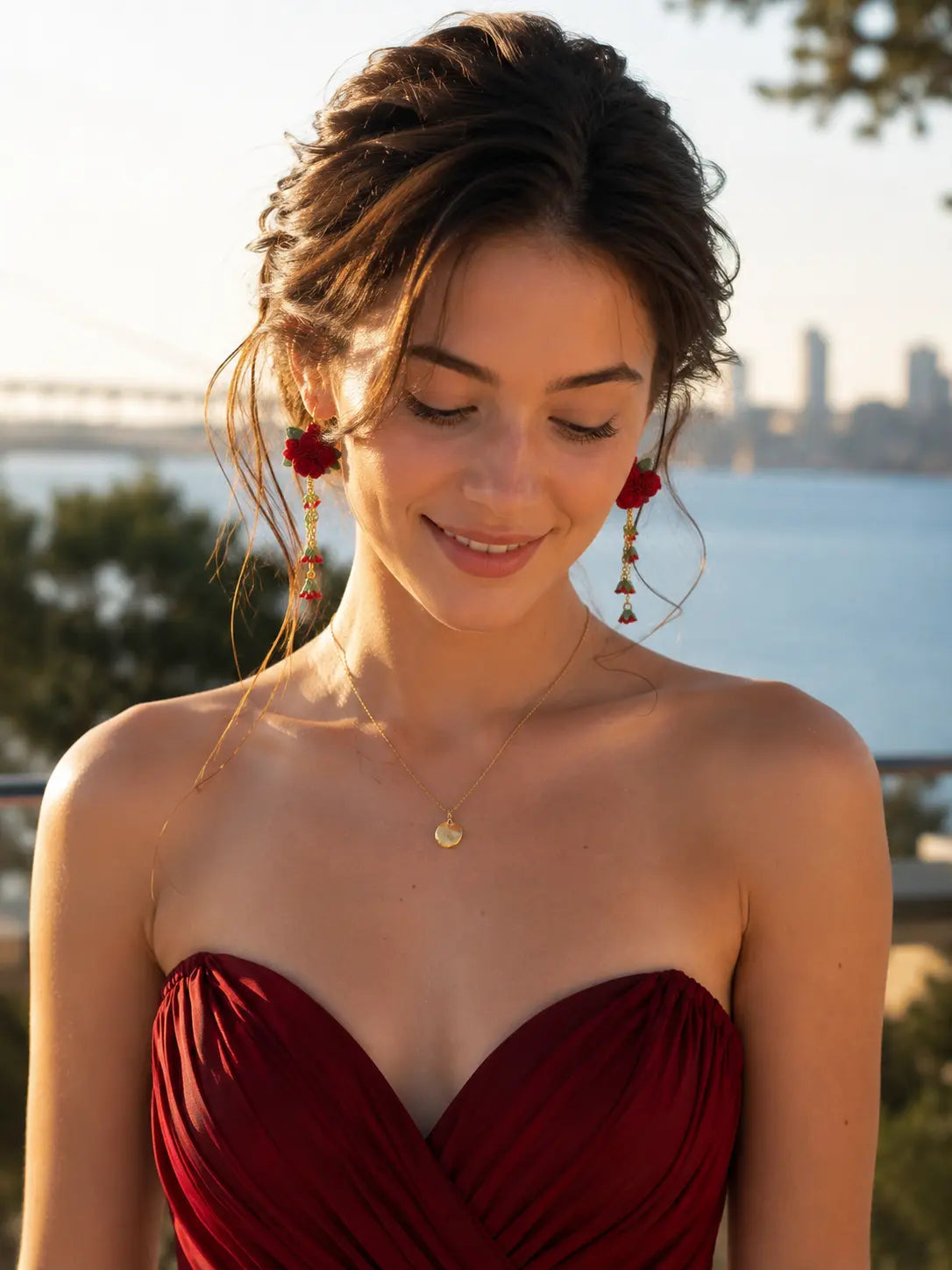 Lifestyle photo of a model wearing micro crochet Rose Cluster Dangle Earrings with a red dress in a warm sunset setting.