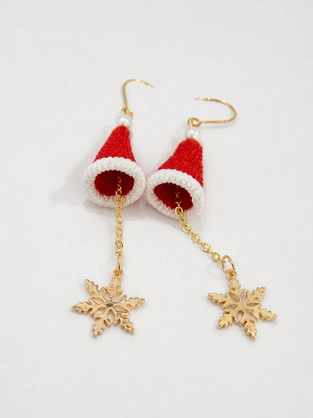 Detailed view of handmade red Santa hat earrings with dangling gold snowflake charms on a white background