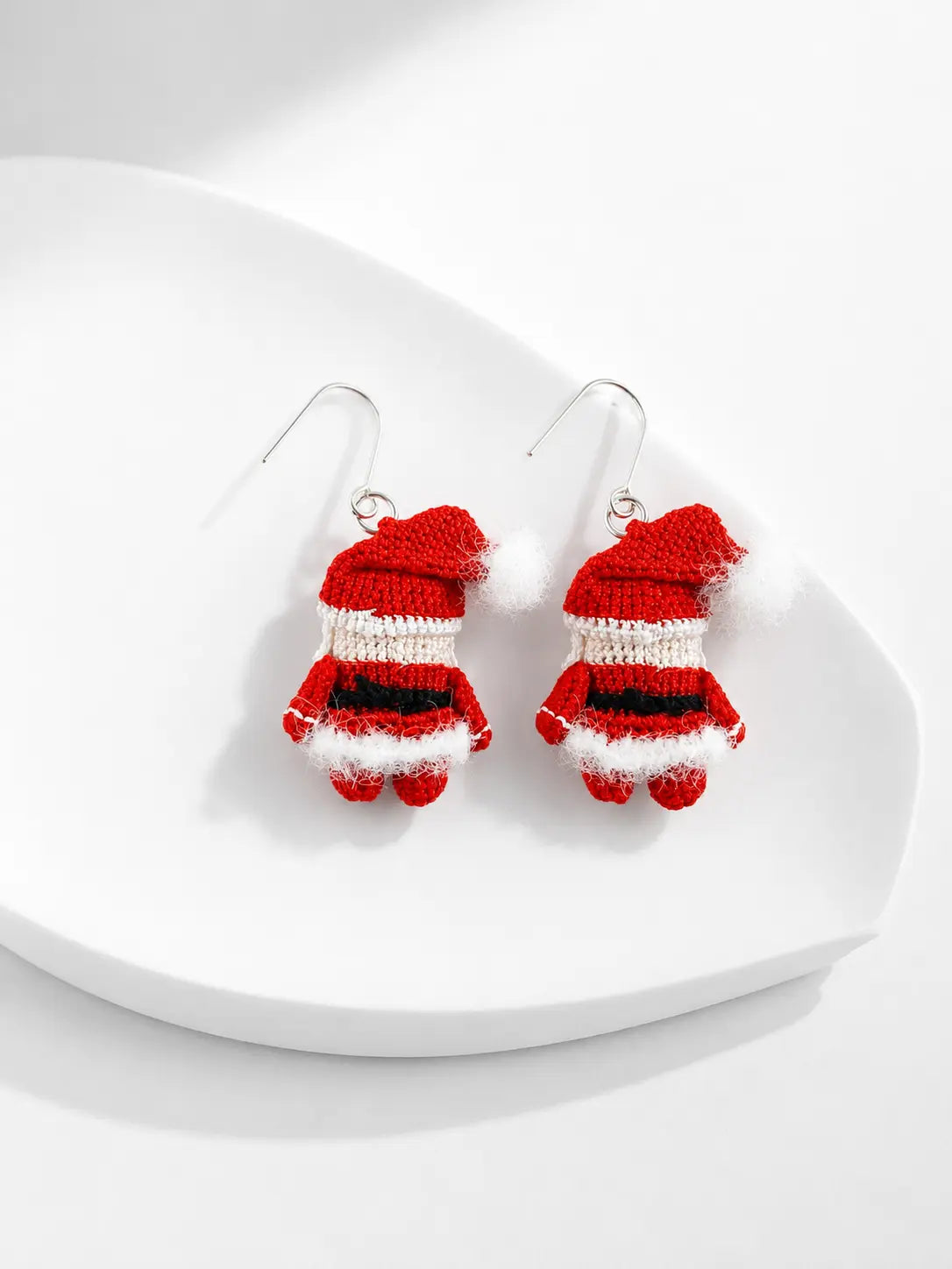 Detailed view of handmade Santa Claus drop earrings on a white plate