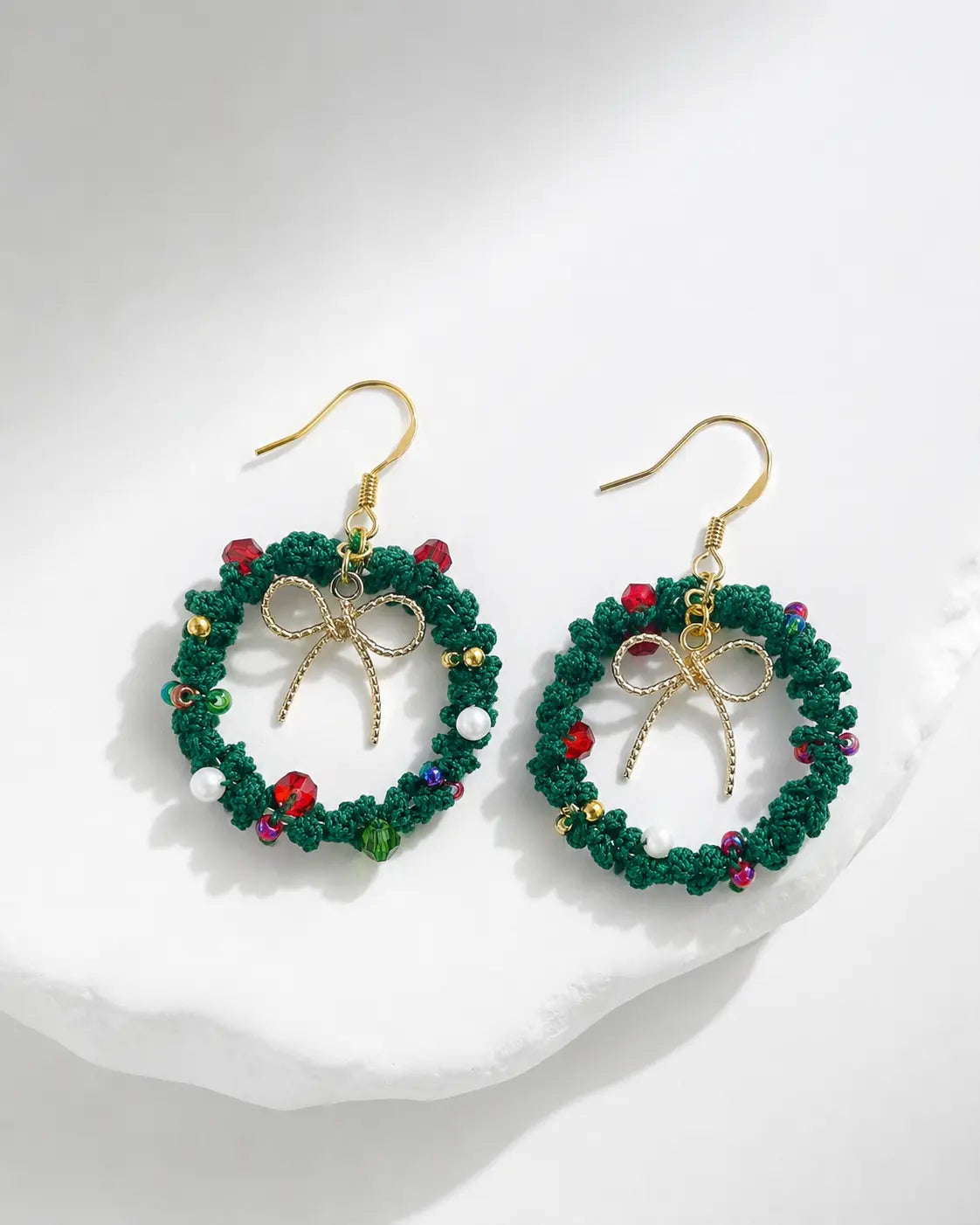 Handmade green Christmas wreath drop earrings with gold hooks, festive bow details and red berry accents on a white background