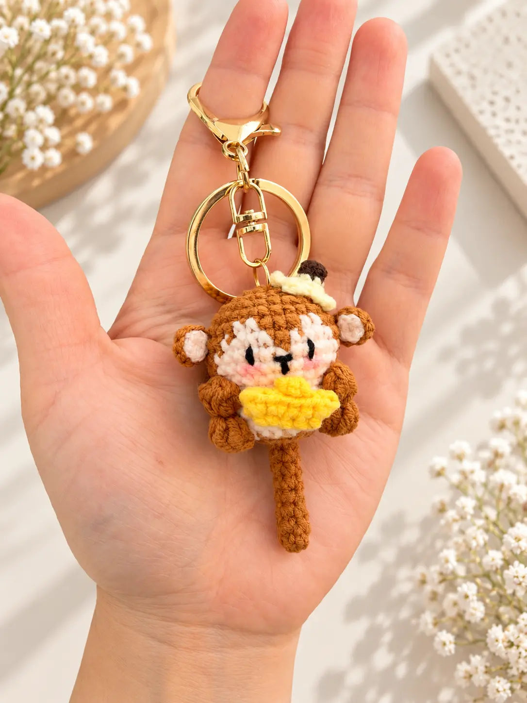 Handmade banana monkey crochet keychain and bag charm held in hand