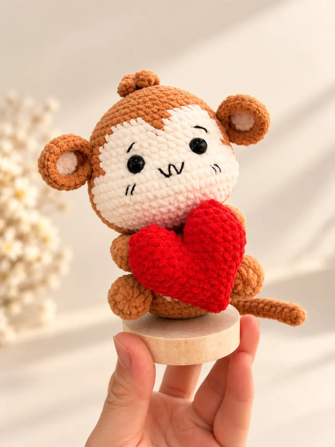 Handmade heart monkey crochet figurine holding a red heart on a small wooden base