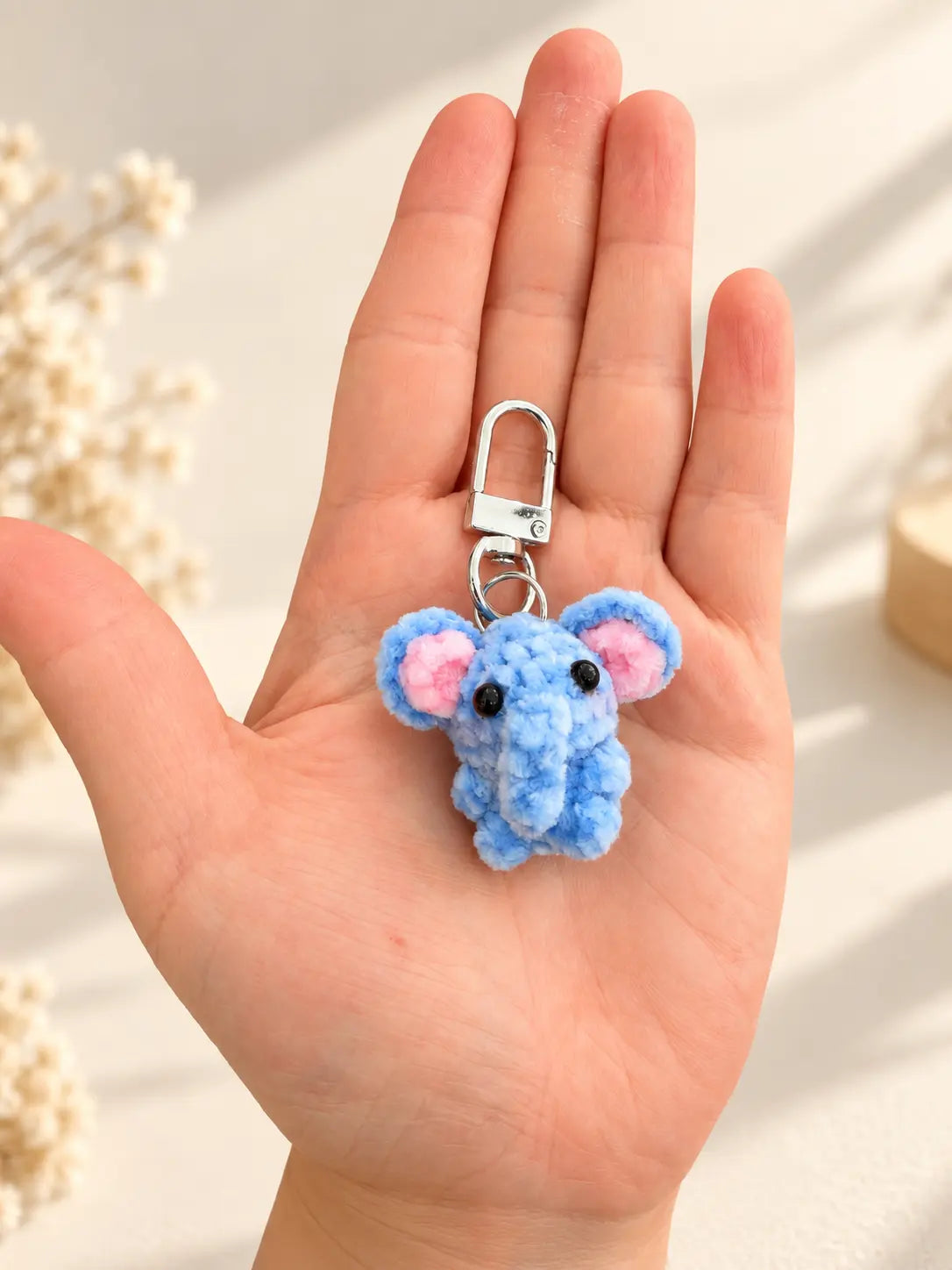 Handmade mini blue elephant crochet keychain and bag charm held in hand
