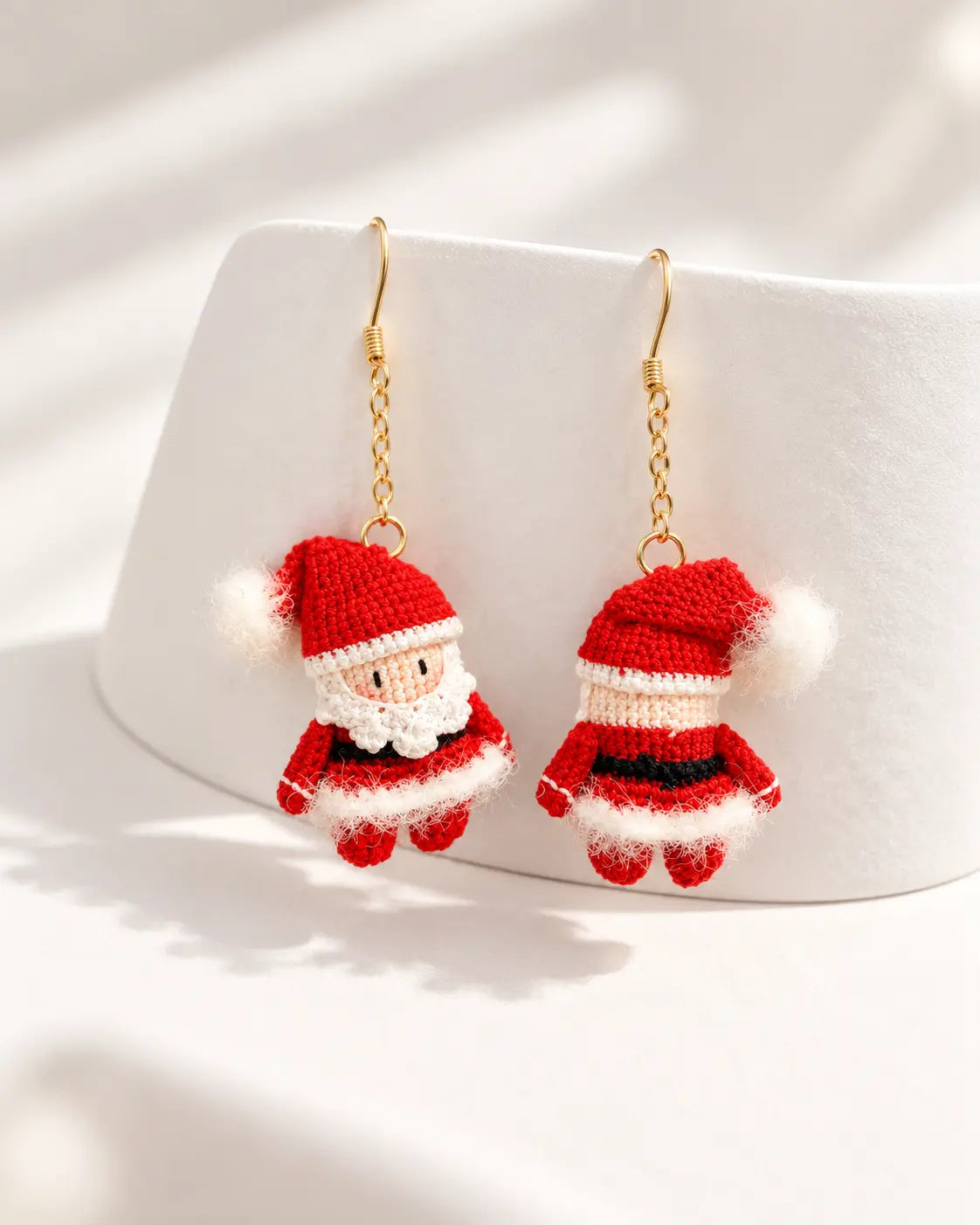 Close-up of handmade miniature Santa Claus crochet earrings showcasing delicate stitching and festive red and white details.