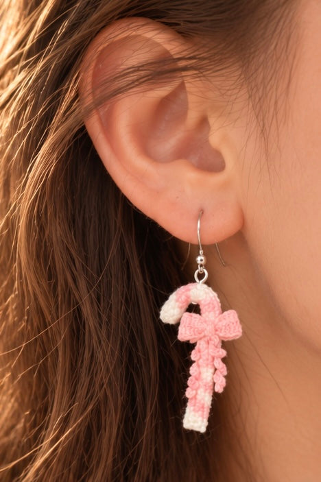 Close-up of handmade pink candy cane crochet earrings